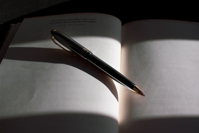 Open book with a pen resting on the blank pages, symbolizing readiness to create new content